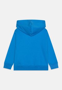 Huppari kirkkaan sinisenä. Valmistettu pehmeästä kankaasta, jossa on kengurun tasku ja ribbiehkaiset hihansuut ja helma. Sileä tekstuuri, yksinkertainen muotoilu.