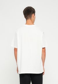 Camiseta blanca de algodón con un corte relajado, manga corta y cuello redondo. Textura suave, sin patrones ni acentos visibles.