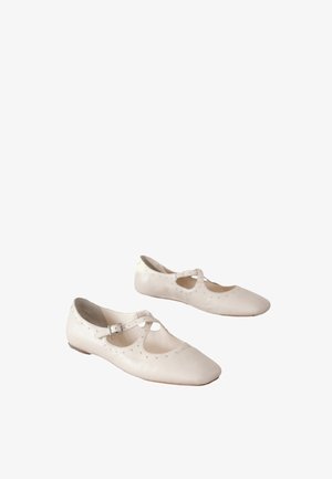 Balta īdas baleta kurpītes ar izgriezuma detaļām un nelielu lencīti. Tās ir dekorētas ar smalkām tapām sānos un ir ar plakanas zolītes.