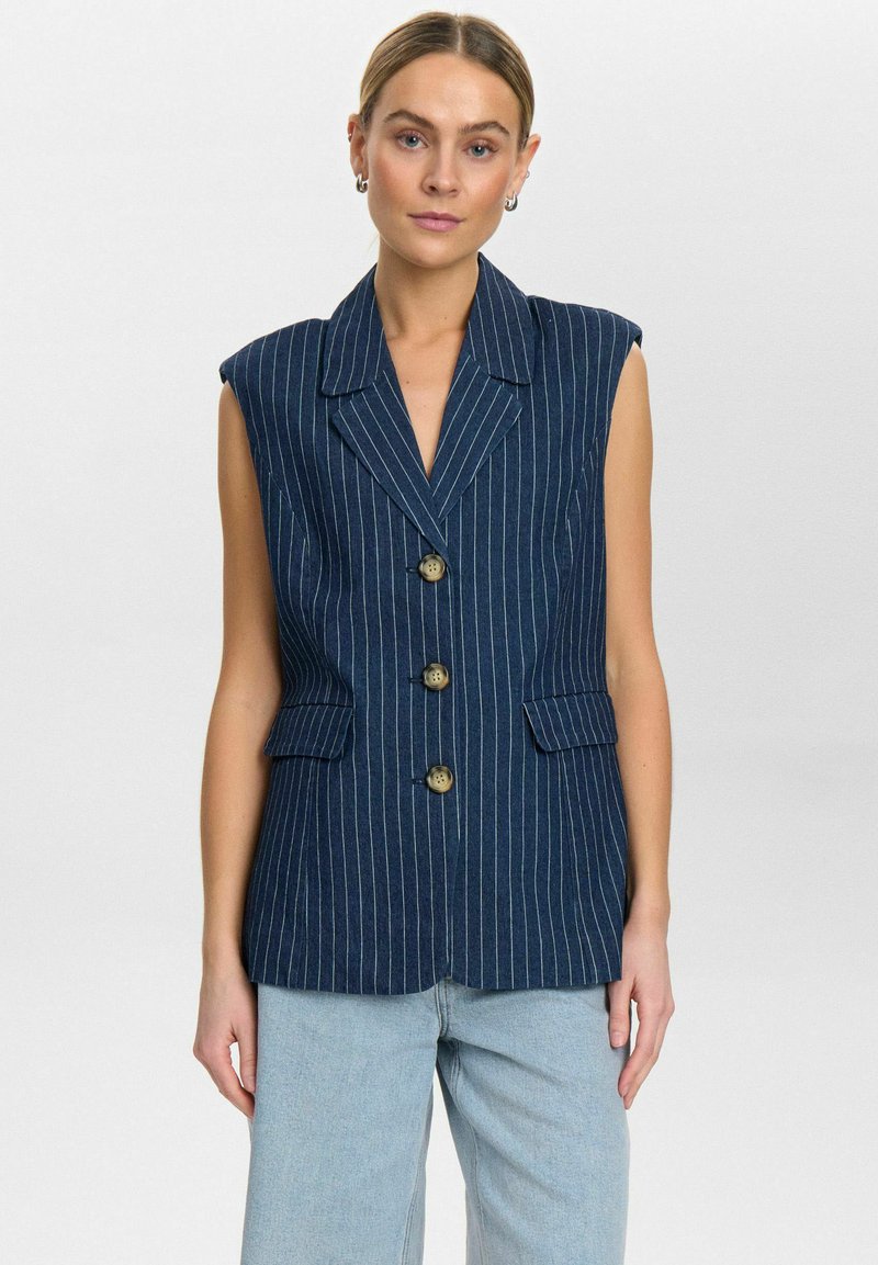 Tumesinine ilma varrukateta bleiser valgete triipudega, klapidega krae, neli messingist nööbi ja kaks esikotti. Tekstuuriga kangas.