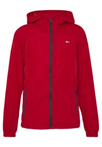 Veste rouge, légère, avec capuche, fermeture éclair intégrale, poignets élastiques et poches latérales. Texture lisse et détails de zipper bleu contrastant.