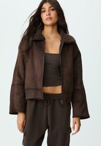 Giacca cropped in finta suede marrone con colletto in pelliccia texturizzata marrone, chiusura con zip, maniche lunghe svasate e tasche laterali.