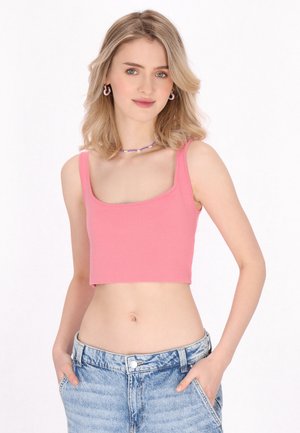 Roze cropped tanktop met een vierkante halslijn en dikke schouderbanden, gecombineerd met lichtblauwe high-waisted denimshorts. De textuur lijkt glad.