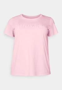 Světle růžové bavlněné tričko s krátkým rukávem a kulatým výstřihem. Na přední straně je vyšitý logo "Levi's". Hladká textura, uvolněný střih.