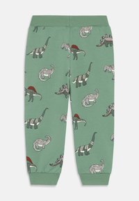 Grüne Kinderhose mit geripptem Bund und Bündchen, ausgestattet mit einem Muster aus verschiedenen illustrierten Dinosauriern in Grautönen und Rot.