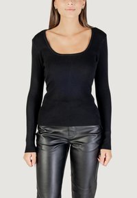 Top lungo a manica nera a costine con scollatura a girocollo, design aderente e tessuto testurizzato, abbinato a pantaloni di pelle nera.