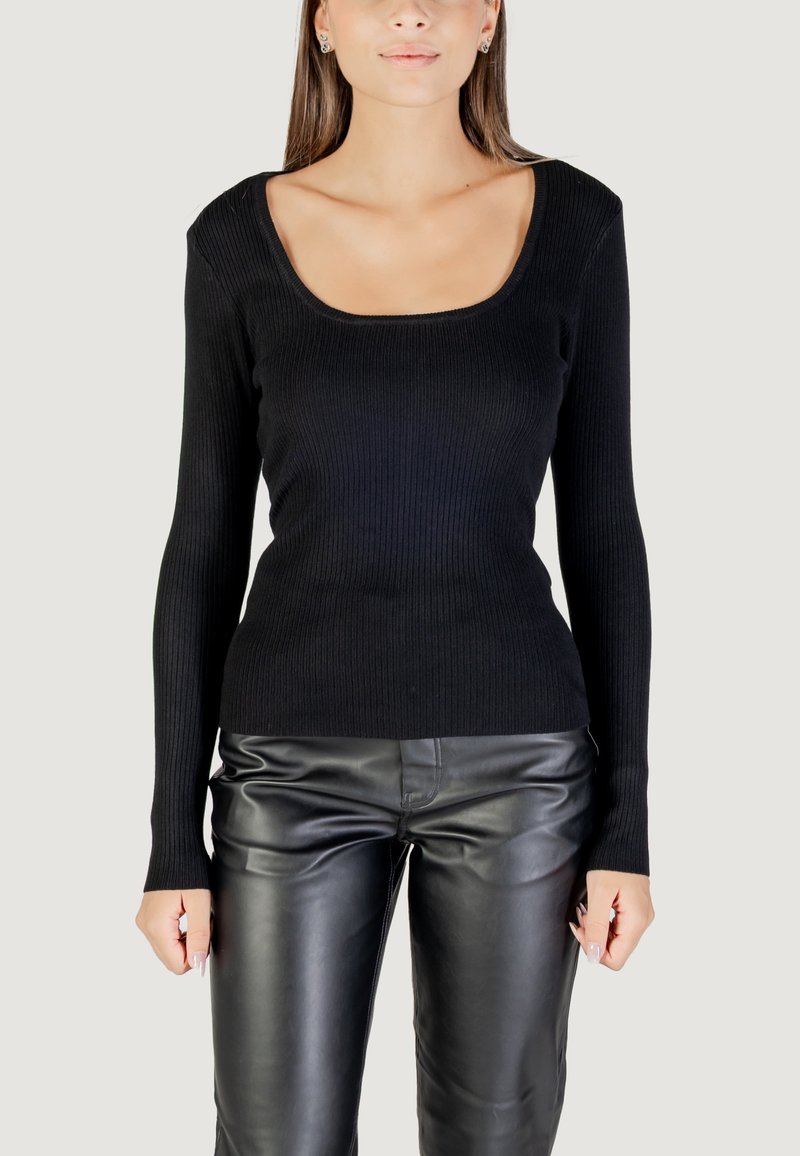 Top lungo a manica nera a costine con scollatura a girocollo, design aderente e tessuto testurizzato, abbinato a pantaloni di pelle nera.