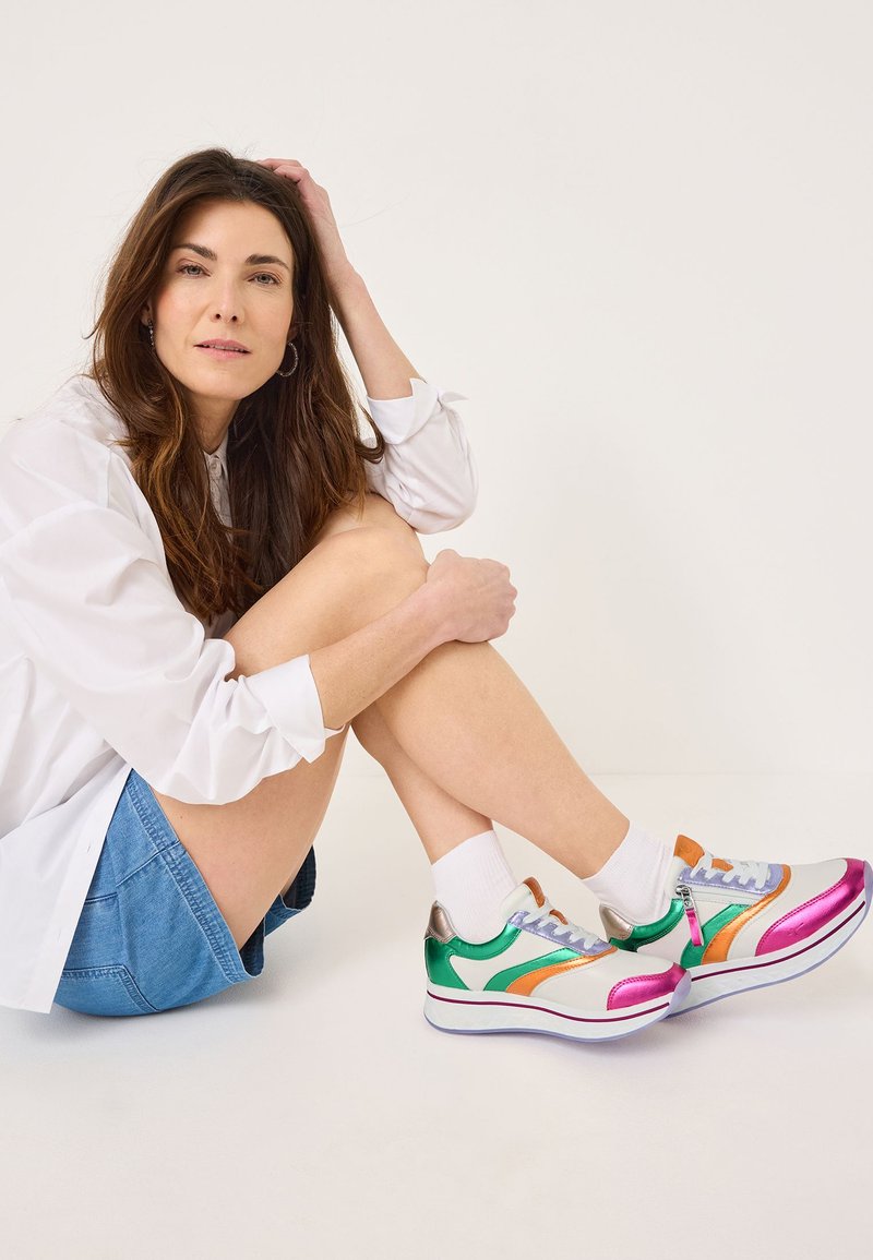 Bunte Turnschuhe mit einer Mischung aus Grün, Orange, Lila und silbernen Akzenten. Sie verfügen über eine glatte Textur, ein Schnürdesign und eine elegante, abgerundete Form.