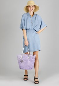 Helles blaues Denim-Hemdkleid mit kurzen Ärmeln, tailliertem Schnitt, kombiniert mit einer lilafarbenen Spitzen-Tote-Bag und schwarzen Sandalen mit Blockabsatz.