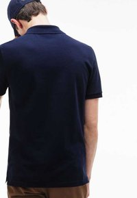 Camisa polo de marinero con cuello clásico, mangas cortas y una textura suave, vista desde la parte posterior. Dobladillo bien terminado y aberturas laterales.