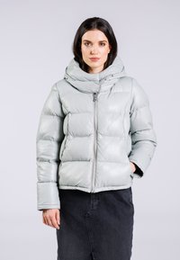 Lys grå pufferjakke med hætte, der har en quiltet design, lynlåslukning og forlommer. Blød, glat tekstur.