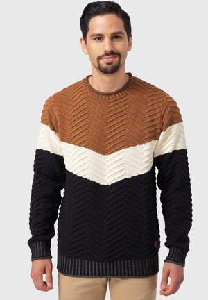 Stickad tröja med ett chevronmönster. Färgblock i brunt, krämfärgad och marinblå. Ribbstickade ärmslut och fåll. Tillverkad av texturerat tyg.