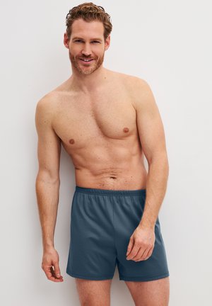 Costume da bagno da uomo blu navy con vita elasticizzata, tessuto leggero e vestibilità comoda. Texture liscia e design semplice senza fantasie.
