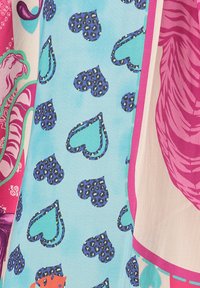 Buntange Stoff hat einen hellblauen Hintergrund mit dunkelblauen Leopardenherzen, angrenzend an ein pinkfarbenes Design mit floralen Elementen.