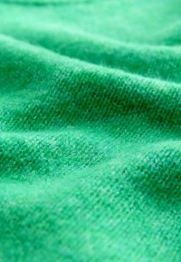 Material verde cu o textură moale, având modele de tricot subtile și nuanțe variate, evidențiind pliuri delicate și adâncime.