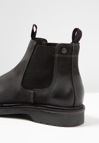 Stivaletto Chelsea in pelle nera con pannello laterale in rete, inserti elasticizzati, linguetta e suola in gomma testurizzata con scanalature orizzontali.