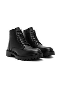 Botas de tobillo de cuero negro con un acabado texturizado, que cuentan con un cierre de cordones en la parte delantera, cremallera lateral y una suela de goma gruesa con un dibujo prominente.