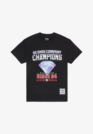 Čierne bavlnené tričko s odvážnou grafickou potlačou s textom "DC Shoe Company," diamantovým tvarom a textom "Champions" v rôznych farbách.