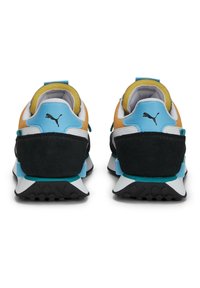 Deux baskets avec un mélange de matériaux. Elles présentent un talon noir, des accents bleus, des côtés orange et blanc, et des semelles texturées. Logo Puma à l'arrière.