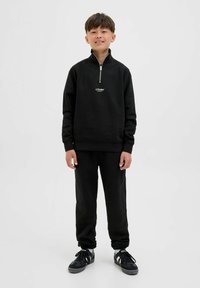 Svart zip-up sweatshirt med logotyp, parat med matchande svarta byxor. Slät tyg, avslappnad passform, ribbade muddar och subtila detaljer.
