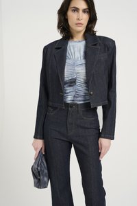 Kort mørk denimjakke med matchende høyde liv bukser. Lys blå mønstret topp under, kombinert med en teksturert grå clutch.
