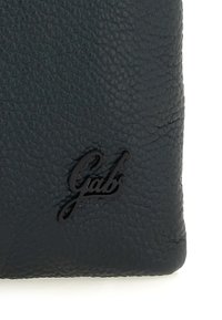 Portafoglio in pelle scura con una trama sottile e un logo nero lucido impresso sulla parte anteriore. I bordi sono arrotondati.