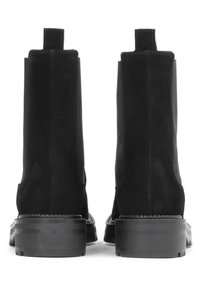 Bottes de cheville en daim noir avec une surface lisse, des panneaux élastiques sur les côtés et des semelles en caoutchouc épaisses. Le design comprend des languettes à l'arrière pour un enfilage facile.