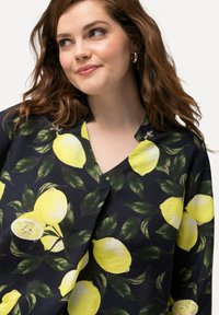 Blusa nera con grande stampa di limoni gialli e foglie verdi, con scollatura a V e tessuto morbido e leggero.