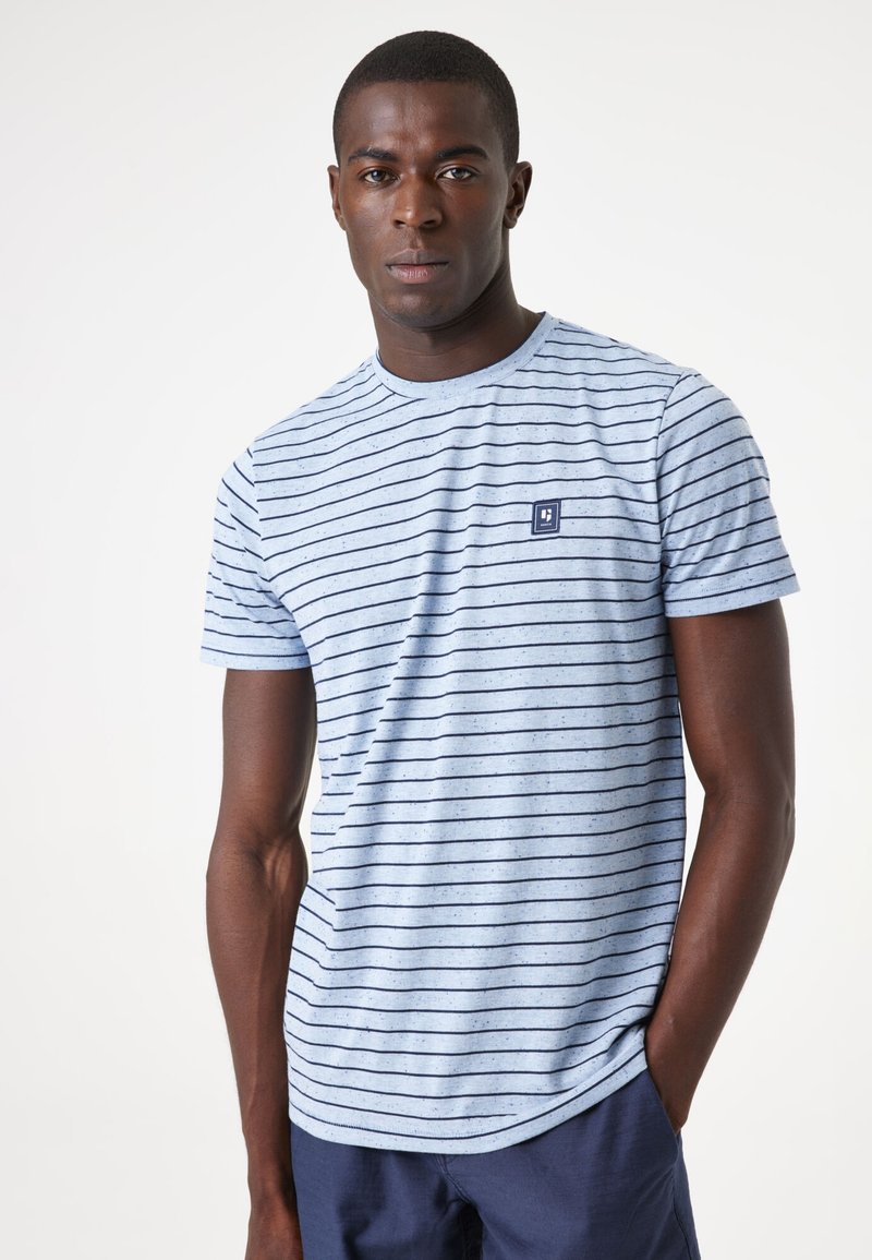 Camiseta azul a rayas de tejido ligero con mangas cortas, que presenta un pequeño logotipo en la parte izquierda del pecho y un cuello redondo.