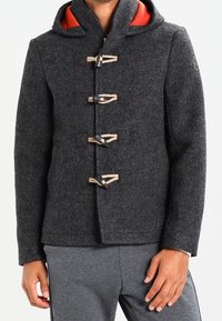 Grå uldjakke med hætte, lukninger med toggles og orange foring. Har en glat tekstur og struktureret design.