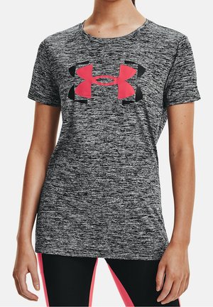 Vrouw draagt een grijs sportshirt met korte mouwen met een groot rood en zwart Under Armour-logo op de borst.
