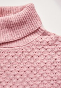 Stickad tröja med en ribbad rosa krage och texturerad kropp, med ett mönster av upphöjda cirkulära mönster och en mjuk yta.