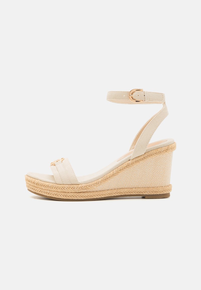 Beige wedge sandaalit, joissa on kangas päällinen, säädettävä nilkkahihna ja juuttiköytetty pohja, jossa on sileä pinta ja kultasävyinen varustus.