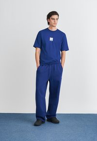 Marineblauw T-shirt met korte mouwen met een klein logo, gecombineerd met bijpassende broek met een verstelbare tailleband en elastische boorden.