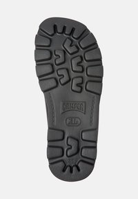 Semelle de chaussure en caoutchouc noir présentant un motif de texture, logo "CAMPER" et empreinte de taille "38". Conçue pour l'adhérence et la durabilité.