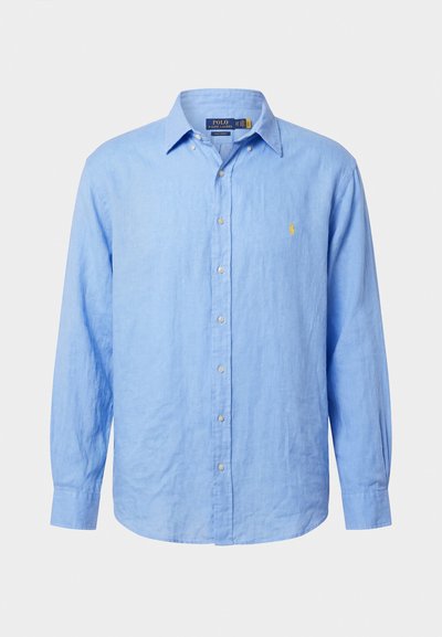 Šviesiai mėlyna ilgomis rankovėmis palaidinė su apykakle ir mažu geltonu siuvinėtu logotipu ant kairės krūtinės.