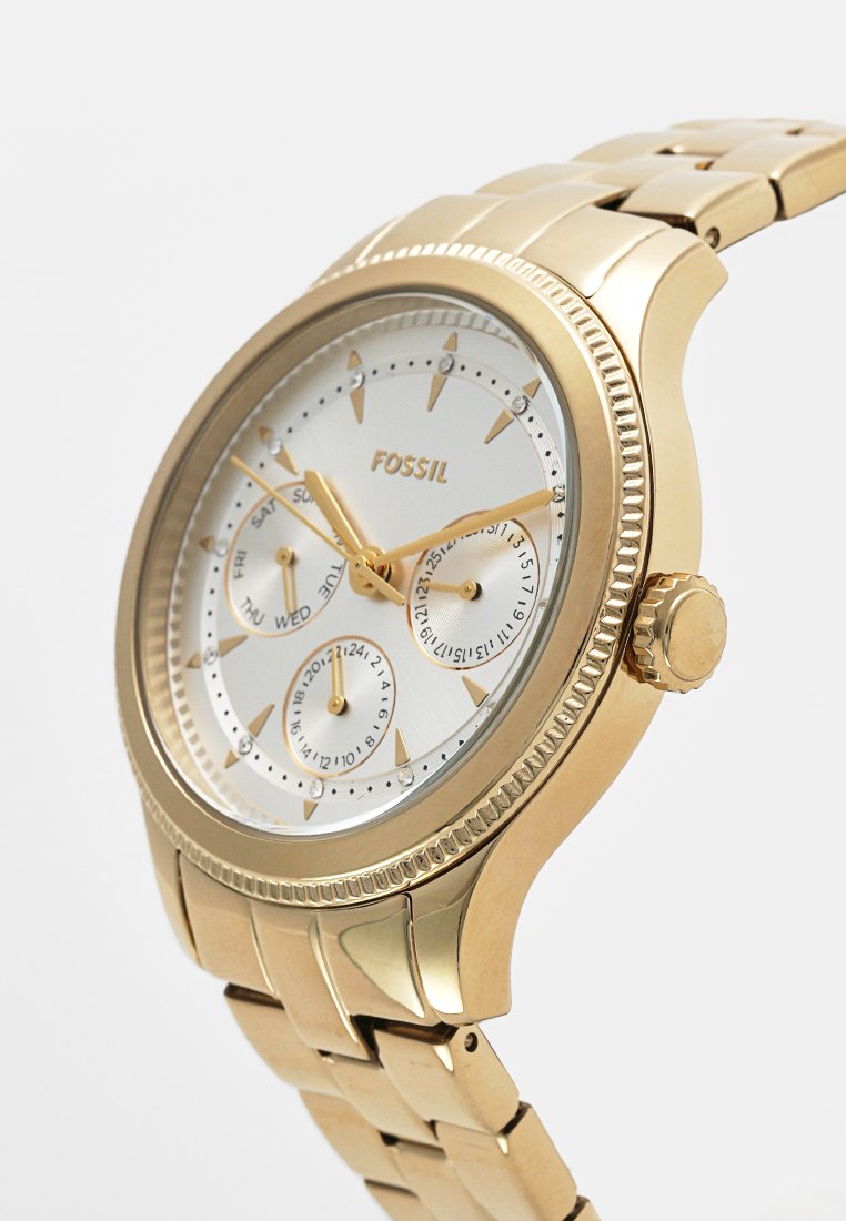 Goldfarbene Fossil-Armbanduhr mit weißem Zifferblatt, drei Unterzifferblätter, die Tag, Datum und 24-Stunden-Zeit anzeigen, sowie einem verknüpften Metallarmband.