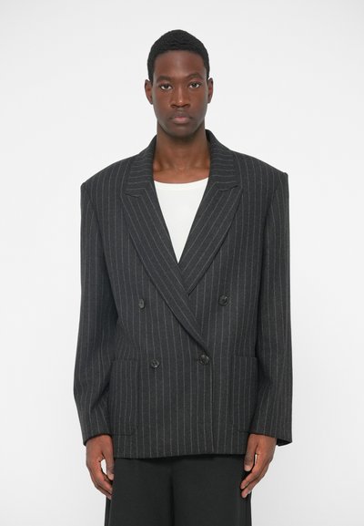 Blazer doppiopetto a righe nere con ampi rever, tasche frontali e spalle strutturate. Tessuto liscio con una vestibilità sartoriale.