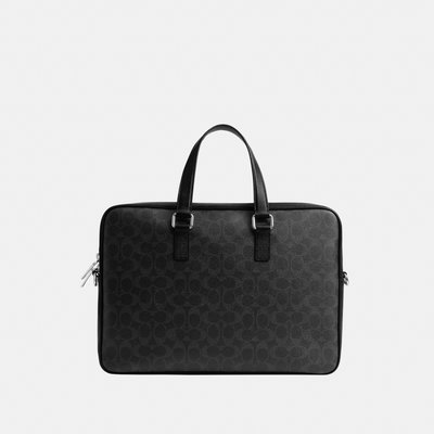 Serviette en cuir noir avec motif discret, doubles poignées et fermetures éclair argentées sur fond gris clair.