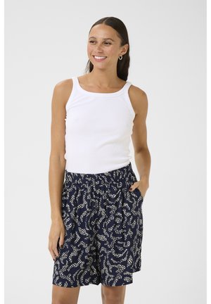 Canottiera bianca e pantaloni corti blu navy con un motivo astratto bianco. I pantaloni corti hanno una vita elastica e tasche laterali.
