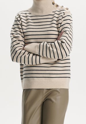Pull en beige à rayures avec des lignes marines, col montant et ourlet côtelé ; présente des accents de boutons sur l'épaule et une texture en tricot douce.