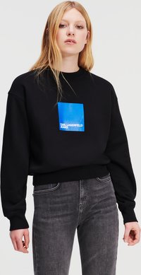 Sudadera negra con un parche cuadrado azul que muestra "KARL LAGERFELD JEANS" en texto blanco, con un corte relajado y puños acanalados.