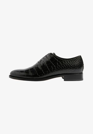 Chaussure Oxford en cuir noir avec texture crocodile, laçage fermé, talon bas et bout pointu, vue de profil sur fond blanc.