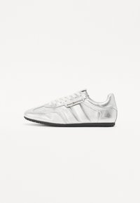 Des chaussures de course argentées avec une finition m�étallique, un design à lacets, trois bandes sur le côté et une semelle en caoutchouc noir.