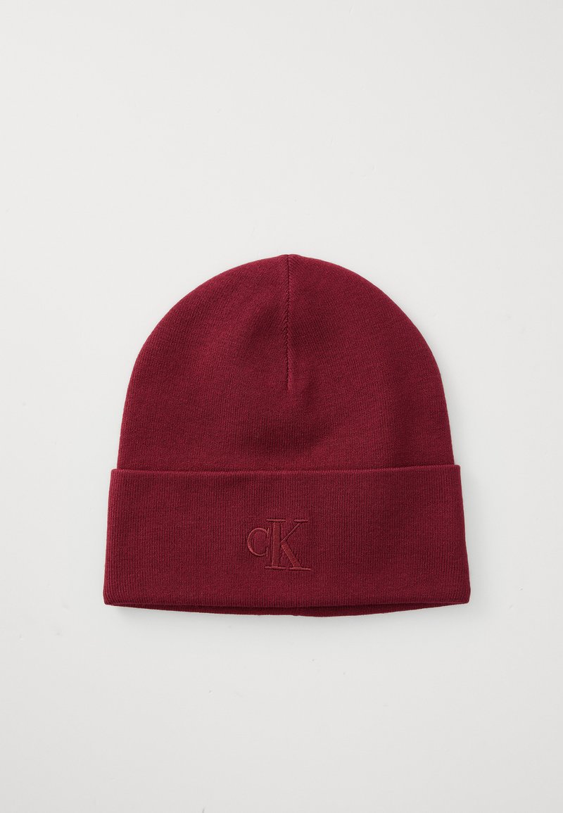 Burgundy knit beanie with a folded cuff and embroidered "ck" logo on the front. Soft texture, snug fit, and simple, streamlined design.