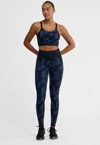 Högpresterande sportbh och leggings i mörkblått med abstrakta geometriska mönster. Tillverkade av elastiskt material för komfort och stöd.