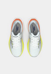 White athletic shoes with a mesh upper, featuring orange and yellow accents. Includes laces and a textured sole. Brand logo visible.