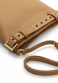 Pruunist pärlmutternahast käekott kullast riistvaraga, perforatsioonidega aktsentide ja eemaldatava rihmaga. Omab tõmbluku sulgemist ja naelutatud detaile.