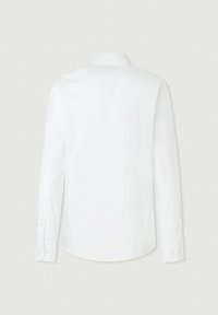 Chemise blanche à manches longues vue de dos avec un col et des poignets boutonnés sur un fond uni.
