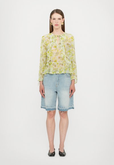 Floral print, sheer light green blouse with ruffles and tie neckline, paired with frayed denim shorts and black flats.